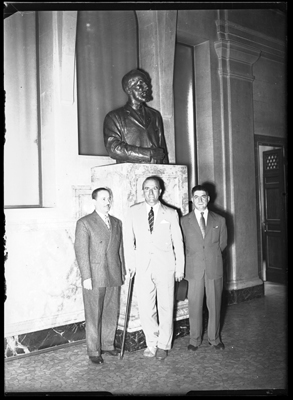 Tre uomini accanto a scultura a mezzo busto della ditta Borsalino di Alessandria
